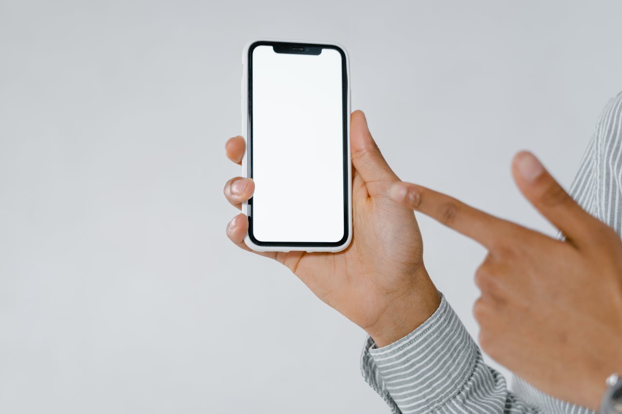 services-03 Detailed image of a person holding and pointing at a smartphone with a blank screen, perfect for mockup use.